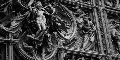 milano italy 米兰大教堂近景，哥特式白色大理石外立面在阳光下闪耀，精细的尖塔与雕像密集排列，游客在广场仰望